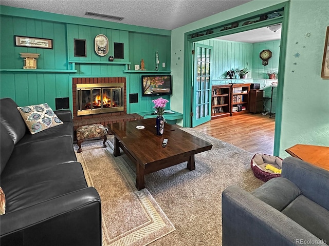 carpeted living area featuring a brick fireplace, a textured ceiling, and visible vents
