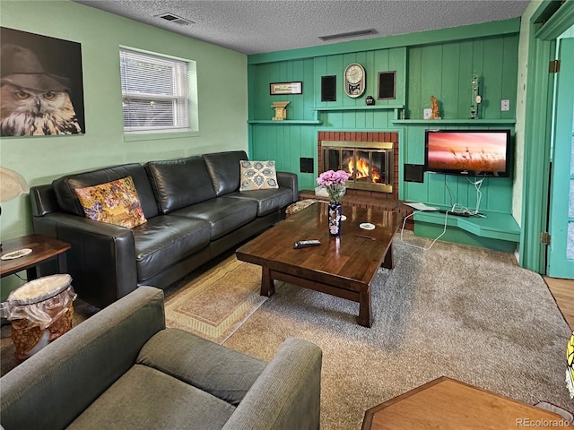 living area featuring wood finished floors, a fireplace, a textured ceiling, and visible vents