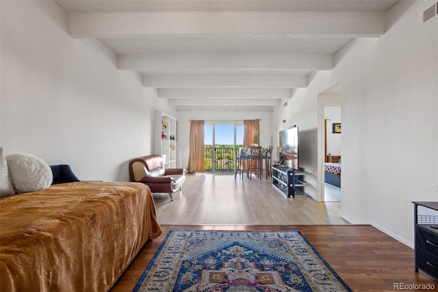 bedroom featuring hardwood / wood-style flooring and beam ceiling