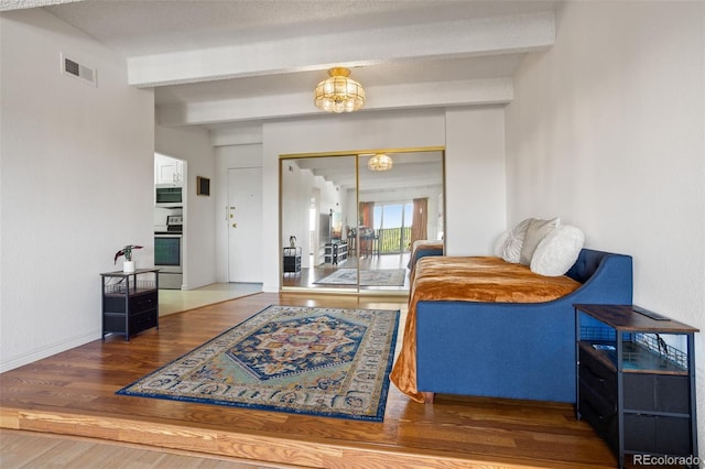 living room with an inviting chandelier, beamed ceiling, and wood-type flooring