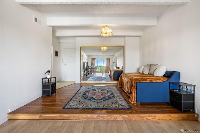 living room with beamed ceiling, dark hardwood / wood-style flooring, a chandelier, and a textured ceiling