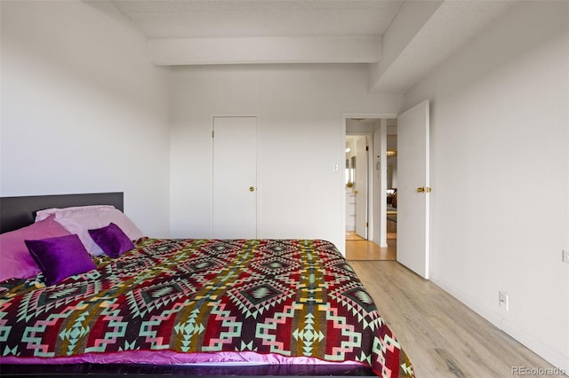 bedroom with vaulted ceiling with beams and light hardwood / wood-style floors