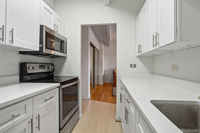 kitchen with light hardwood / wood-style flooring, sink, stainless steel appliances, and white cabinets