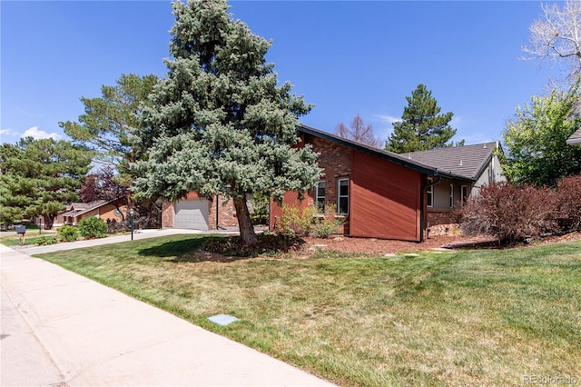 view of front facade with concrete driveway, a front lawn, and brick siding
