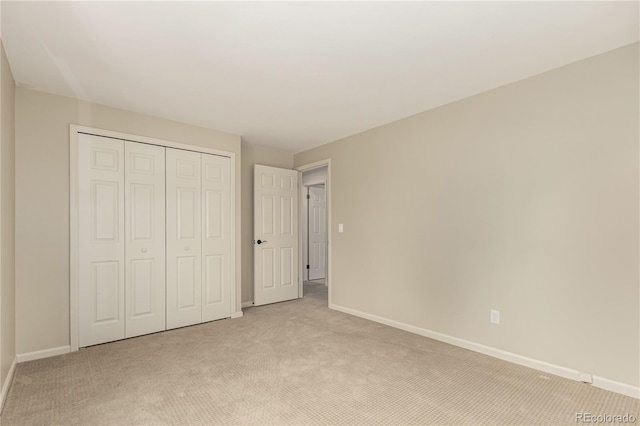 unfurnished bedroom featuring baseboards, light carpet, and a closet