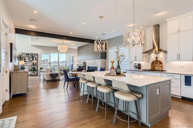 10119 Bellwether Ln, Lone Tree, CO 80124 - kitchen featuring wall chimney range hood, an inviting chandelier, a center island, stainless steel gas stovetop, and tasteful backsplash