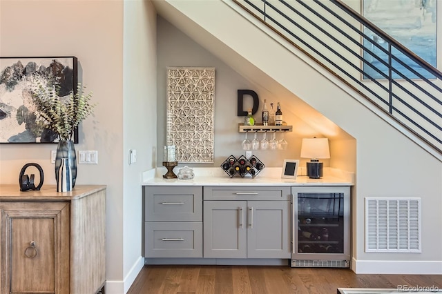 10119 Bellwether Ln, Lone Tree, CO 80124 - bar with visible vents, wood finished floors, beverage cooler, baseboards, and a bar