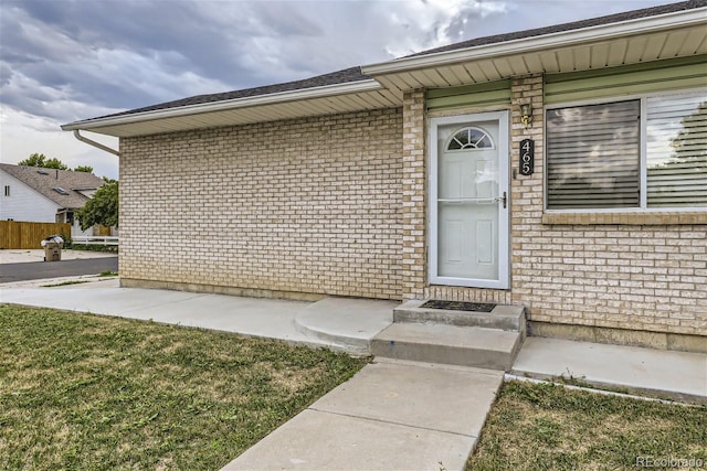 doorway to property with brick siding and fence