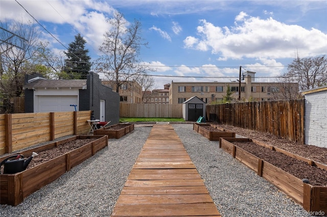 view of yard with a storage shed, a vegetable garden, a fenced backyard, an outdoor structure, and a residential view