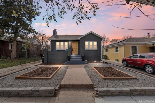 bungalow with brick siding, a vegetable garden, and a chimney