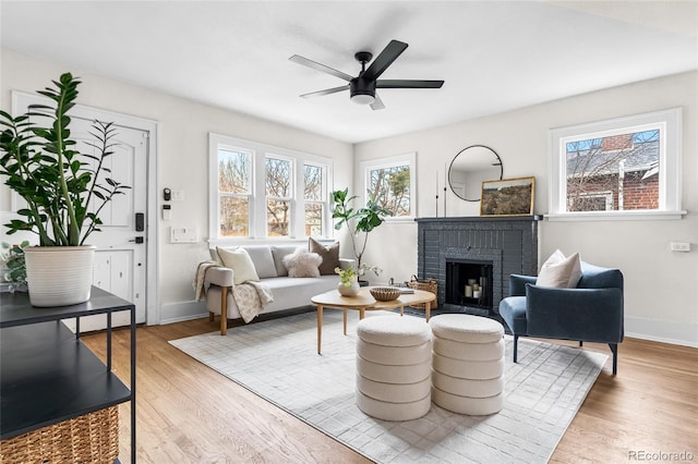 living room with wood finished floors, baseboards, and a brick fireplace