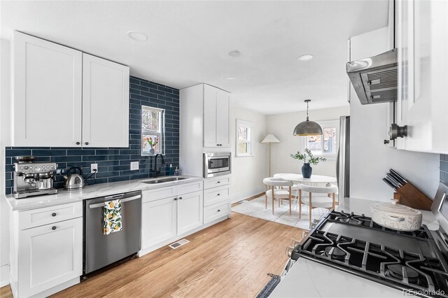 kitchen featuring light countertops, a sink, stainless steel appliances, extractor fan, and backsplash