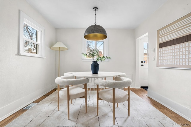 dining space with visible vents, a wealth of natural light, wood finished floors, and baseboards