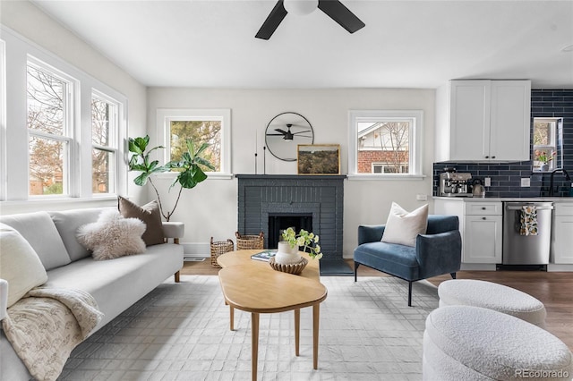 living room with a brick fireplace, a ceiling fan, and plenty of natural light