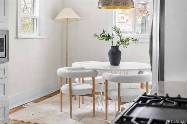 dining space with light wood-style flooring and baseboards