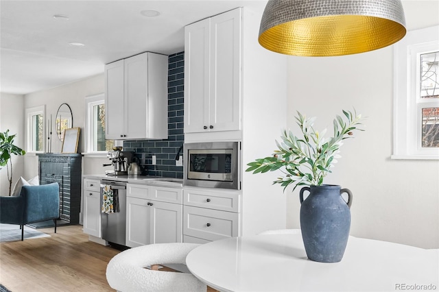 kitchen featuring decorative backsplash, appliances with stainless steel finishes, wood finished floors, and white cabinets