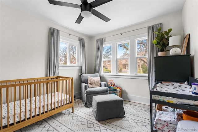 bedroom with baseboards, a ceiling fan, and a nursery area