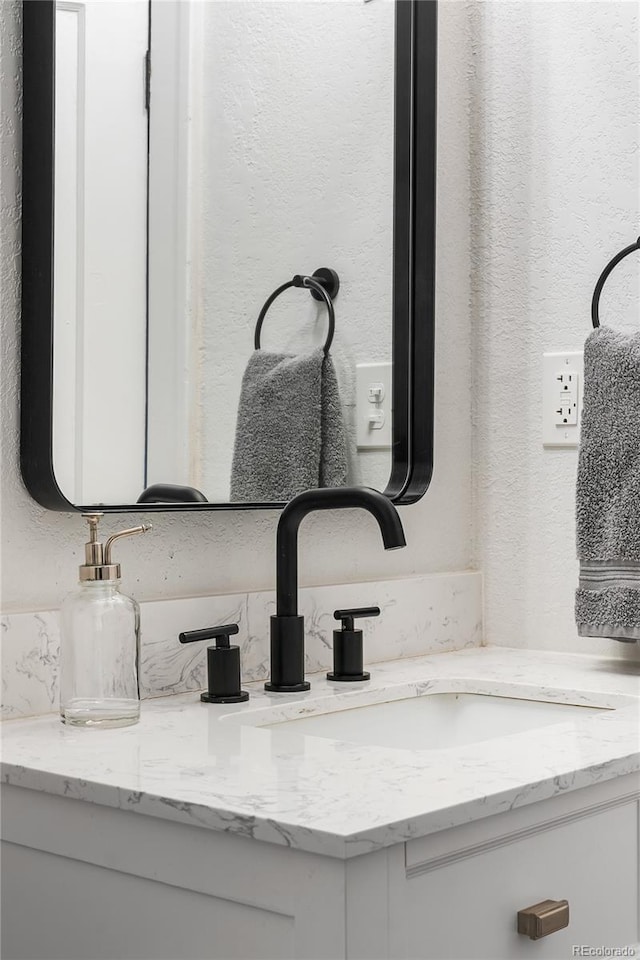 room details featuring vanity and a textured wall