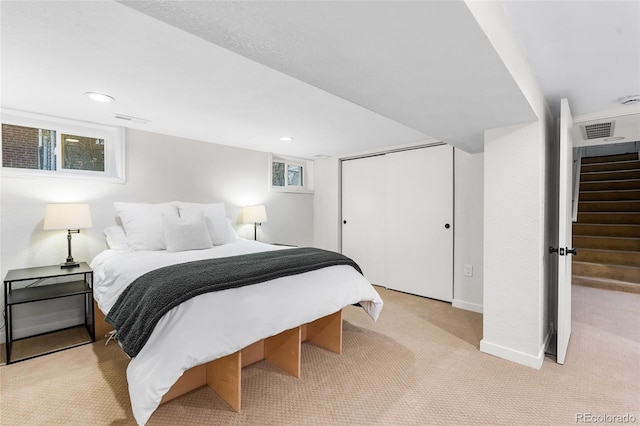 bedroom featuring light carpet, a closet, baseboards, and visible vents