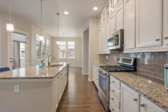 3336 Goodyear St, Castle Rock, CO 80109 - kitchen with appliances with stainless steel finishes, backsplash, dark wood-style flooring, a center island with sink, and white cabinetry