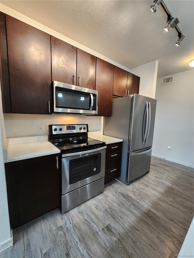9220 Wilde Ln Unit 102, Parker, CO 80134 - kitchen with appliances with stainless steel finishes, light wood-style flooring, light countertops, dark brown cabinets, and track lighting