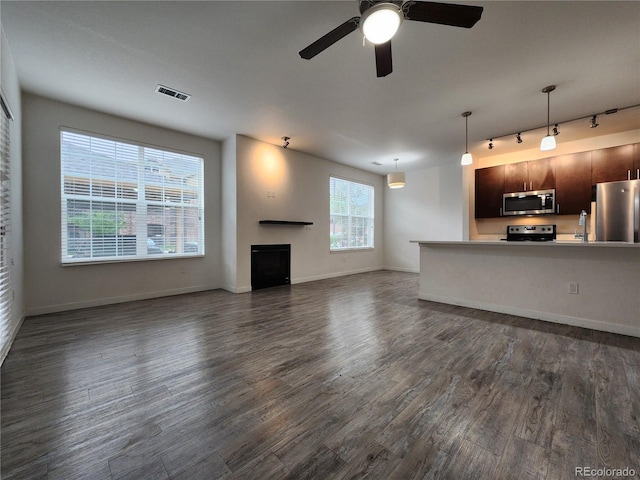 9220 Wilde Ln Unit 102, Parker, CO 80134 - unfurnished living room featuring rail lighting, dark wood-type flooring, ceiling fan, a fireplace, and baseboards