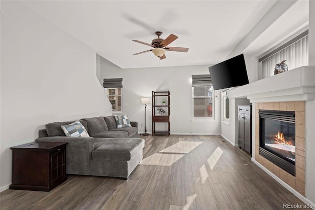 living room with hardwood / wood-style flooring, ceiling fan, and a tile fireplace