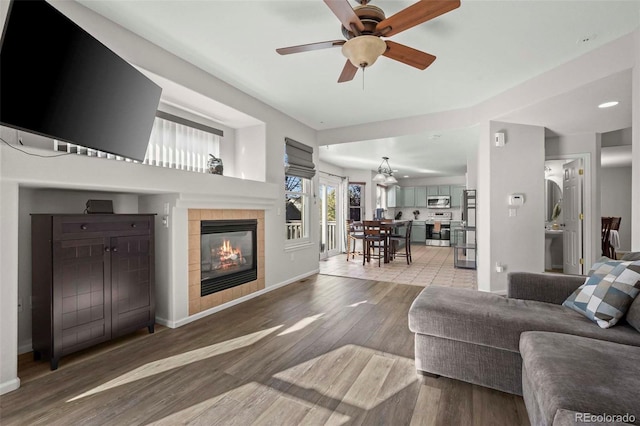 living room featuring a tile fireplace, ceiling fan, and hardwood / wood-style floors