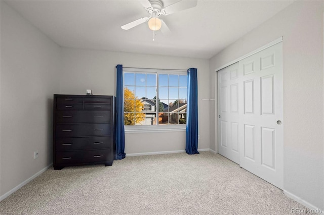 unfurnished bedroom with a closet, light colored carpet, and ceiling fan