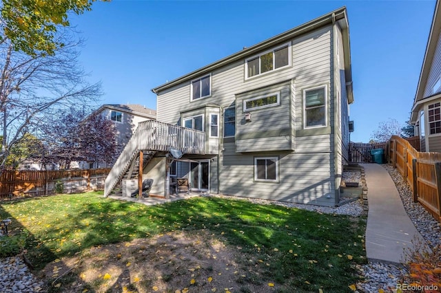 back of property featuring a wooden deck, a patio area, and a lawn