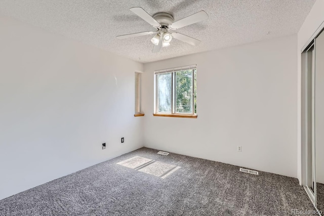 unfurnished bedroom featuring visible vents, a textured ceiling, carpet flooring, and a ceiling fan