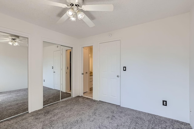 unfurnished bedroom with carpet flooring, ceiling fan, a textured ceiling, and multiple closets