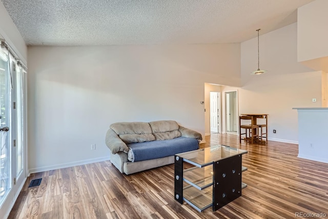 living room with visible vents, a textured ceiling, and wood finished floors