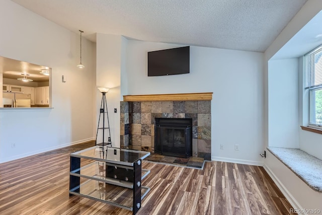 living area with lofted ceiling, wood finished floors, baseboards, and a textured ceiling