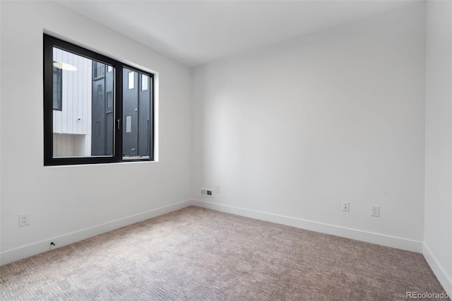 spare room featuring carpet flooring, visible vents, and baseboards