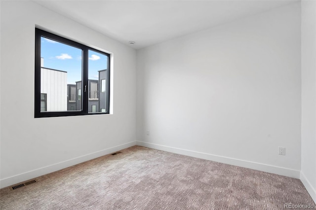 spare room featuring carpet, visible vents, and baseboards