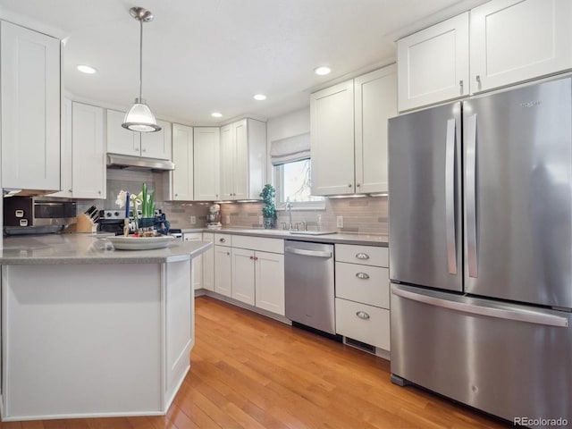 kitchen featuring pendant lighting, white cabinets, appliances with stainless steel finishes, sink, and light wood-type flooring