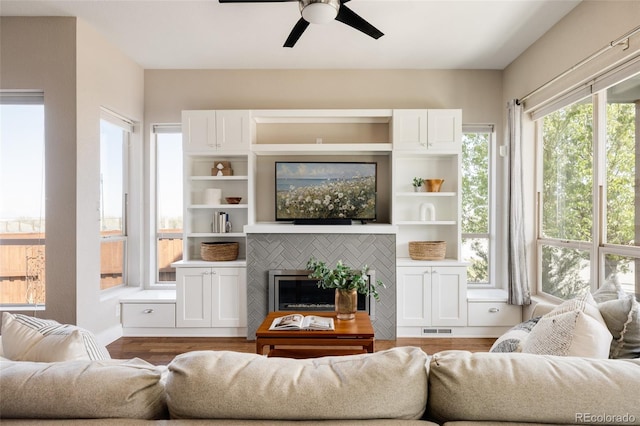 living room featuring visible vents, ceiling fan, wood finished floors, and a fireplace