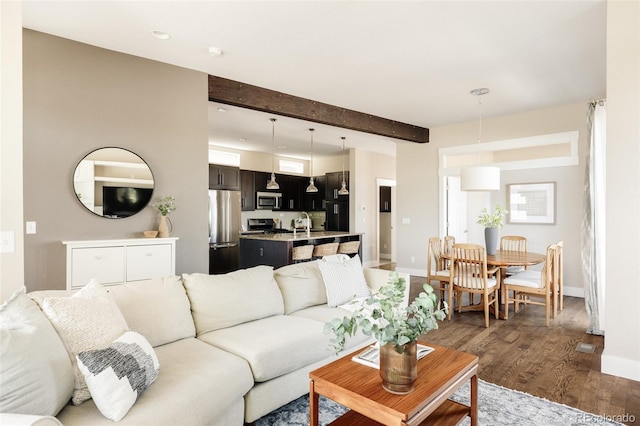 living room with baseboards, recessed lighting, beamed ceiling, and wood finished floors