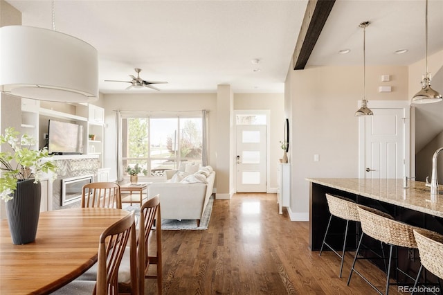 dining space with ceiling fan, a fireplace, recessed lighting, baseboards, and wood finished floors