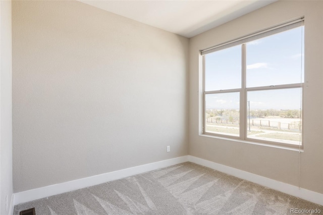 spare room with baseboards, light colored carpet, plenty of natural light, and visible vents