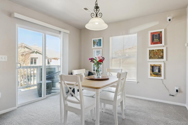 dining area featuring baseboards, visible vents, and light colored carpet