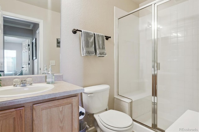 bathroom featuring a textured wall, a shower stall, toilet, and vanity