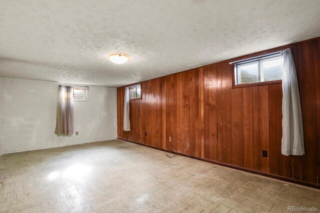 basement featuring a textured ceiling and wood walls