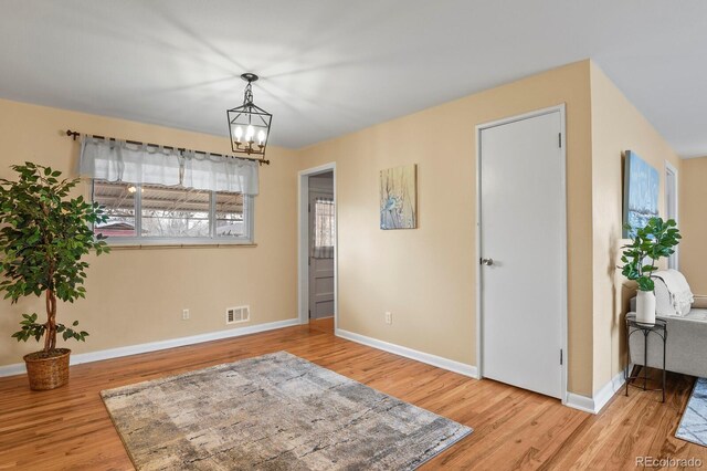 unfurnished room featuring an inviting chandelier and light hardwood / wood-style flooring