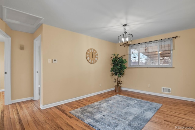 unfurnished room with an inviting chandelier and light hardwood / wood-style flooring