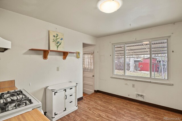 kitchen featuring white cabinetry, white gas range, and light hardwood / wood-style flooring