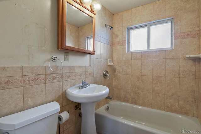 bathroom with tiled shower / bath, tile walls, and toilet