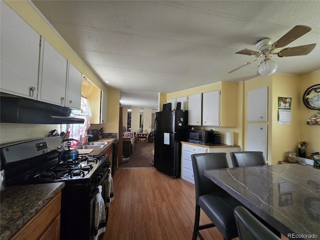 602 Vine St, Salida, CO 81201 - kitchen with black appliances, under cabinet range hood, a sink, light wood finished floors, and dark countertops