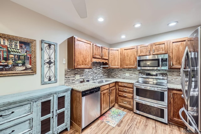 3022 S Wheeling Way S Unit 410, Aurora, CO 80014 - kitchen with appliances with stainless steel finishes, a sink, light stone countertops, light wood finished floors, and decorative backsplash